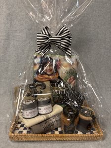 Image of the Taste of France prize basket which contains a jar of Bonne Maman jam, a jar of Maille mustard, a container of Taste of Provence spices, a container of Taste of Bordeaux spices, a lined kitchen towel set, a container of French sea salt, a wicker and abalone checkerboard serving tray, a copy of Ina Garten's cookbook Barefoot in Paris.